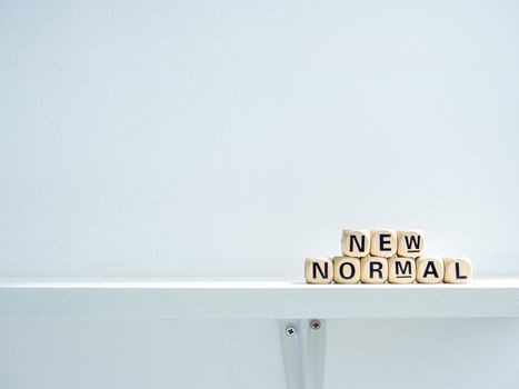 New Normal, words on wooden alphabet cube on shelf on white background with copy space. New normal after covid-19 pandemic concept.