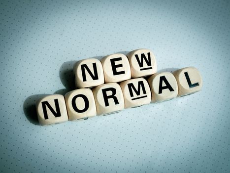 Close-up New Normal, words on wooden alphabet cube on dark background, top view. New normal after covid-19 pandemic concept.