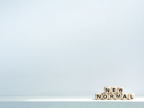 New Normal, words on wooden alphabet cube on shelf on white background with copy space. New normal after covid-19 pandemic concept.