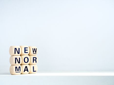 Close-up New Normal, words on wooden alphabet cube on shelf on white background with copy space. New normal after covid-19 pandemic concept.