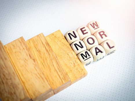 Stairs down to New Normal, words on wooden alphabet cube on white background, top view. New normal after covid-19 pandemic concept.