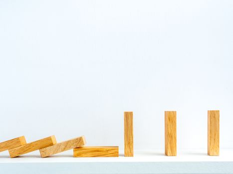Social Distancing concept. Row of falling and standing wooden dominoes with distance space on shelf on white background with copy space.