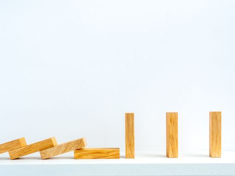 Social Distancing concept. Row of falling and standing wooden dominoes with distance space on shelf on white background with copy space.