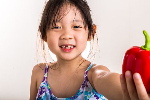 Child is holding a red pepper in her hand background.