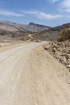 Unpaved road in rocky and wild mountains of the Sultanate of Oman.This path is close to Wadi Bani Khalid, a famous wadi where there penty of water and where we can enjoy swimming, contrasting with this arid and dry area.