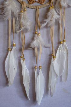 Closeup of white dream catcher a small white hoop decorated with feathers and beads.