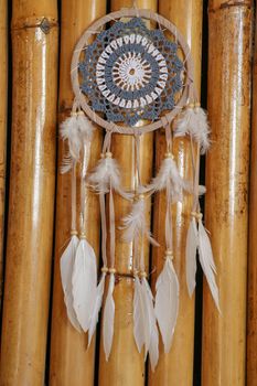 Blue Dreamcatcher with feathers and beads isolated on a wodden background.
