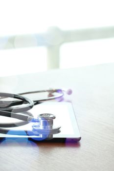 Studio macro of a stethoscope and digital tablet with shallow DOF evenly matched abstract on wood table background copy space