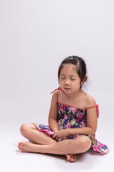 Little girl does mediation alone on with white background.