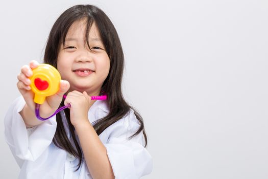 Young little girl dressing doctor with medical instrument in hands.