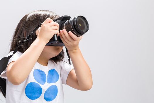 Little kid using DSLR camera to take some photos in studio.