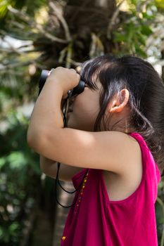 Cute girl is looking through binoculars during a trip.