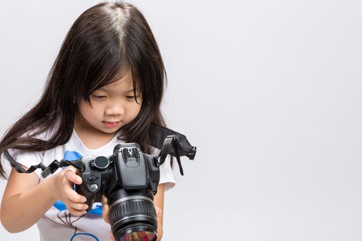 Little kid using DSLR camera to take some photos in studio.