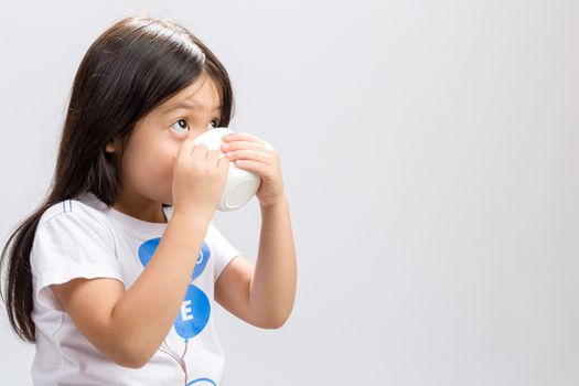 Kid drinking milk on studio isolated white background.