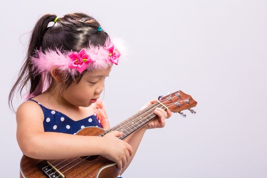 Little girl with her ukulele, string music instrument.