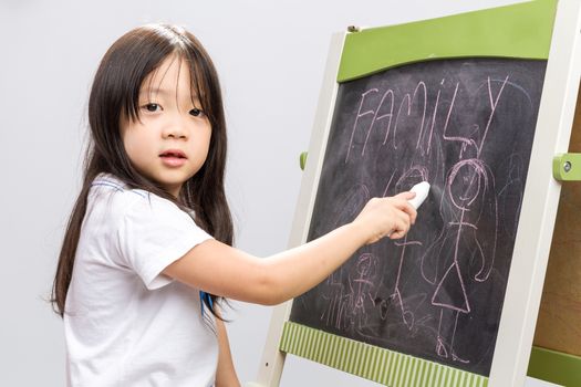 Little kid writing something on blackboard studio isolated.