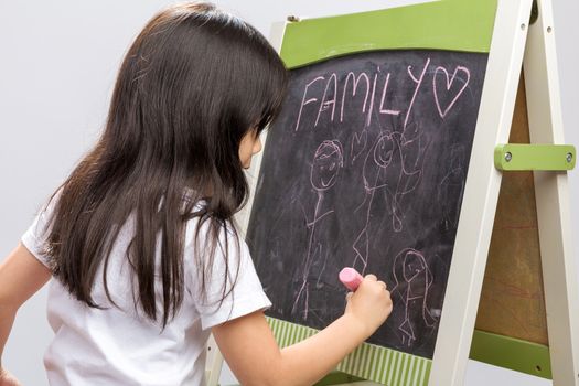 Little kid writing something on blackboard studio isolated.