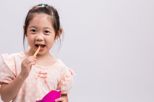 Little girl is eating French fries with happiness.