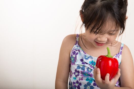 Child is holding a red pepper in her hand background.