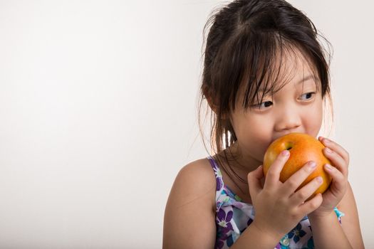 Little girl takes a bite of apple in her hands.