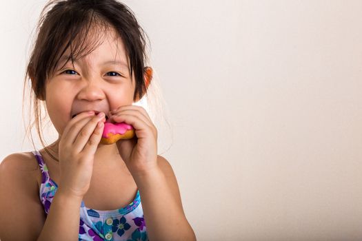 Little girl is eating her donut with happiness.