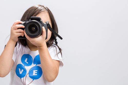 Little kid using DSLR camera to take some photos in studio.