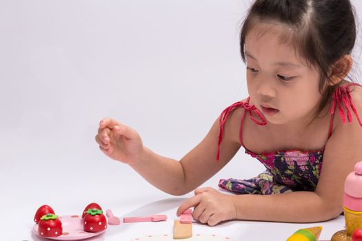 Happy little girl is playing with her cooking toy set.