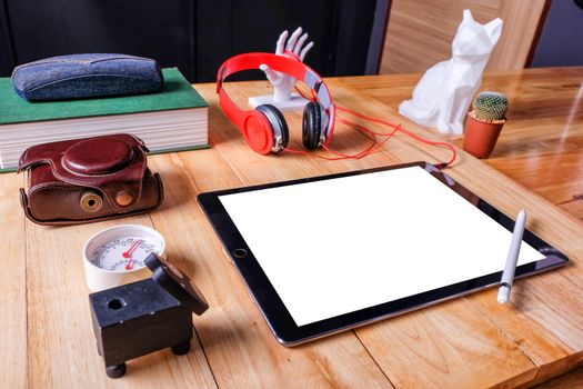 Office workplace with tablet and headphone on wood table.