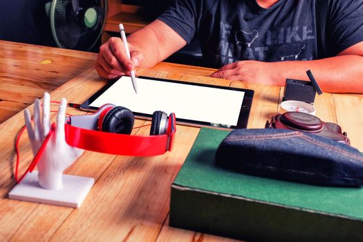 Office workplace with tablet and headphone on wood table.