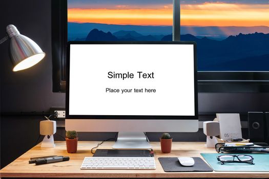 Graphic designer's workspace equipped with a pen tablet, a computer and white screen for text with beautiful sunset on moutain from the window 