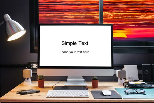 Graphic designer's workspace equipped with a pen tablet, a computer and white screen for text with beautiful sunset on moutain from the window 