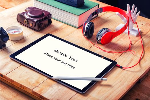 Office workplace with tablet and headphone on wood table.