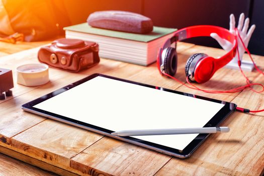 Office workplace with tablet and headphone on wood table.