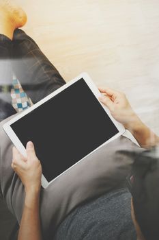 top view of hipster hands using digital tablet pro while sitting on a cosy sofa in his home as concept