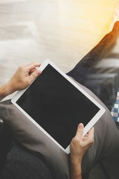 top view of hipster hands using digital tablet pro while sitting on a cosy sofa in his home as concept