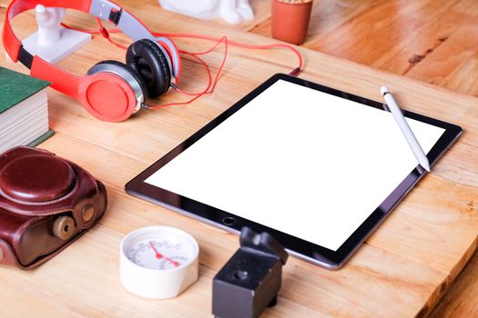 Office workplace with tablet and headphone on wood table.