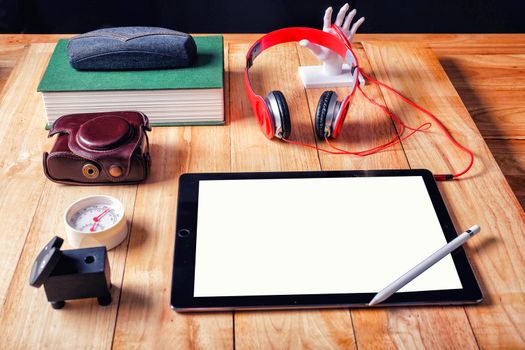 Office workplace with tablet and headphone on wood table.