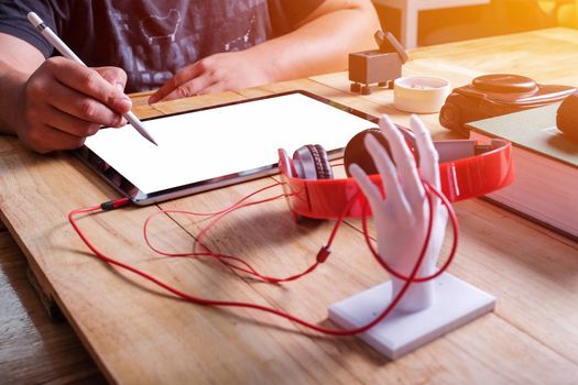 Office workplace with tablet and headphone on wood table.