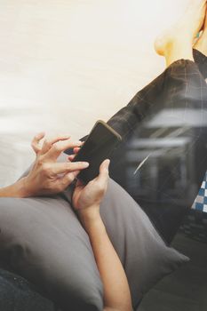 top view of hipster hands using smart phone while sitting on a cosy sofa in his home as concept