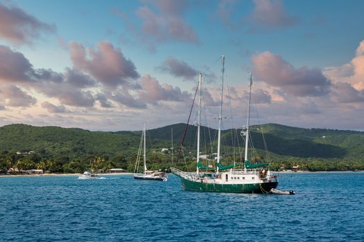 A three masted sailboat moored in a calm Caribbean harbor