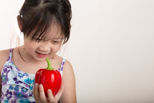 Child is holding a red pepper in her hand background.