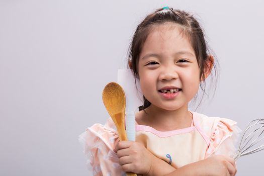 Happy little girl holding kitchenware in her hands.