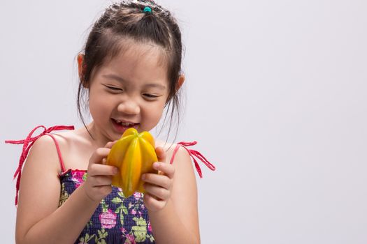 Child is holding a star apple in her hands background.