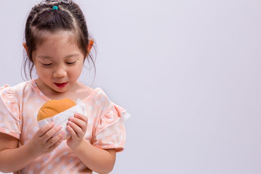 Little girl is eating hamburger with happiness.