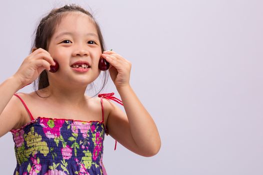 Child is holding cherry in her hand background.