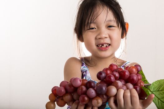 Child is holding grapes in her hands background.