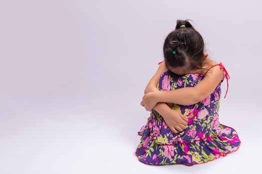 Little girl with lonely emotion sitting alone by herself.