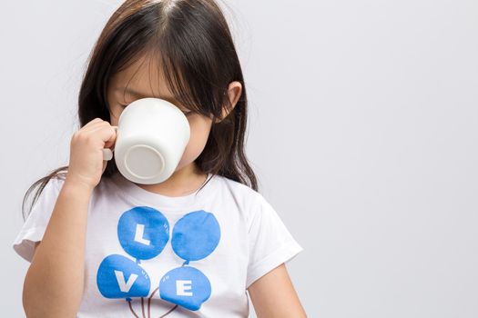 Kid drinking milk on studio isolated white background.