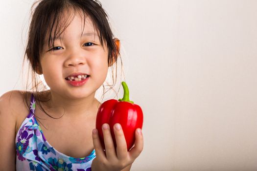 Child is holding a red pepper in her hand background.