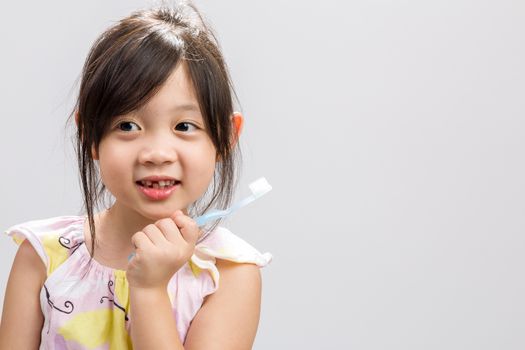 Cute Asian girl brushing teeth, studio isolated white background.